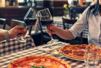 Verliebtes Paar stoßen auf Ihre Lieben an, halten Hand in einem Restaurant und essen Pizza und trinken Rotwein