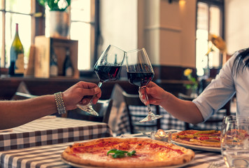 Verliebtes Paar stoßen auf Ihre Lieben an, halten Hand in einem Restaurant und essen Pizza und trinken Rotwein