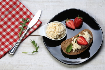 Slices of bread with white cheese and strawberries on top