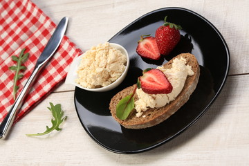 Slices of bread with white cheese and strawberries on top