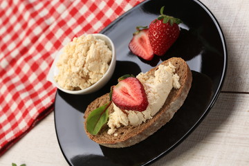 Slices of bread with white cheese and strawberries on top