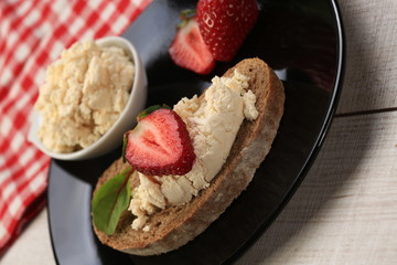 Slices of bread with white cheese and strawberries on top