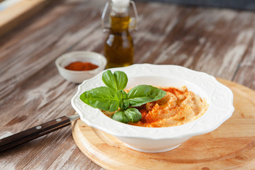 Fresh classic hummus with basil in the bowl on wooden background