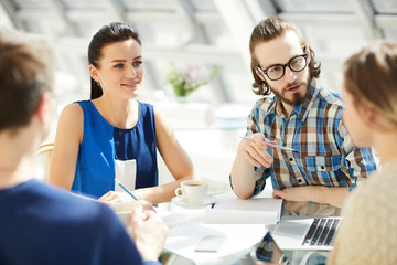 Obraz premium Meeting of young creative start-upers discussing new ideas for grand working project