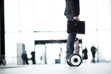 Side view of businessman in formalwear standing on hoverboard and moving straight