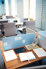 Nobody by workplace with tablet, papers, notebook and other office supplies near by in open space
