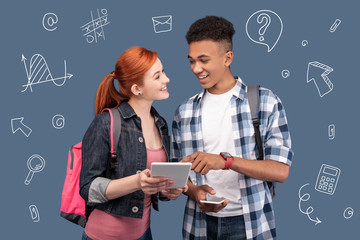 Friendly classmates. Friendly positive classmates standing together and looking happy while...
