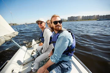 Fotobehang Zeilen Actieve mannen in zonnebril zittend op jacht terwijl ze drijven in het meer op een warme zomerdag