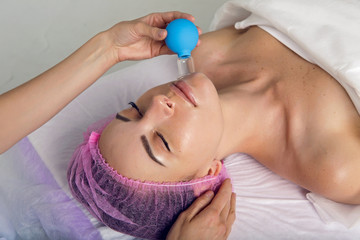 doctor cosmetologist makes Bank with suction Cup patient