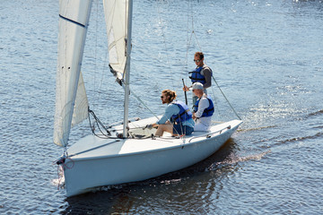 Fototapeta premium Three men in lifejackets sitting in yacht and sailing in the sea during weekend trip