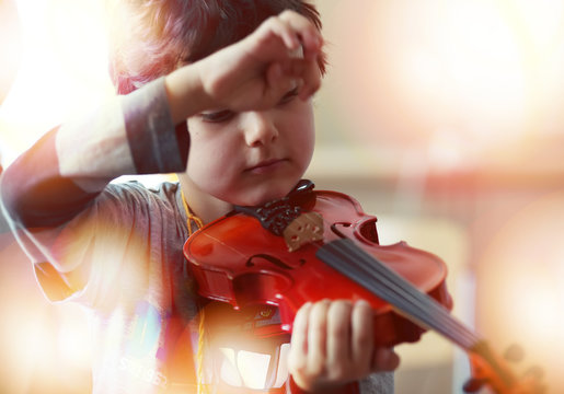Child playing the violin in  room
