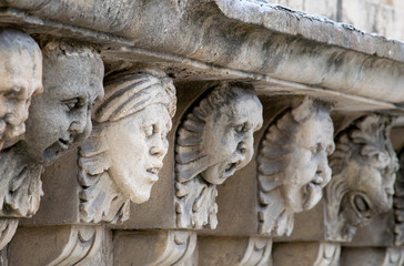 Closeup view of mascarons with  funny faces under the balcony of a baroque palace in the province of Syracuse, Sicily