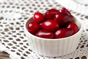Fresh cornel berries in a white bowl.