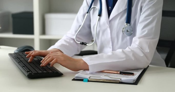 Cropped image of female doctor typing on keyboard .