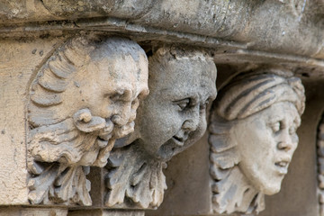 Closeup view of mascarons with  funny faces under the balcony of a baroque palace in the province of Syracuse, Sicily