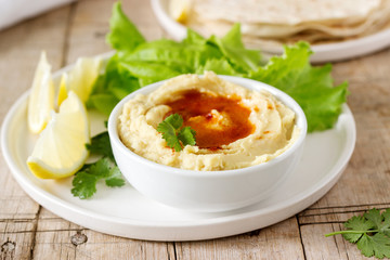Hummus with olive oil and paprika, served with pita, lemon and lettuce leaves.