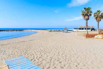 View of beautiful sandy beach with palm trees near Marbella town, Andalusia, Spain
