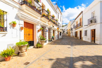 Narrow street with houses in white Andalusian village with typical Spanish architecture, Zahara de la Sierra, Spain - obrazy, fototapety, plakaty