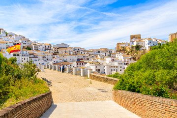 Fototapeta premium SENTINEL DE LAS BODEGAS, SPAIN - MAY 13, 2018: Two men standing on viewpoint and looking at beautiful white village with church on hill. Spain is second most visited by tourists country in Europe.