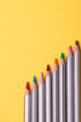 Set of colored pencils for drawing on a yellow background.