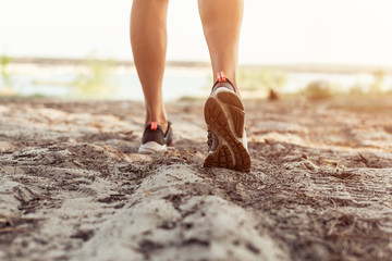 Close up of the legs of a young woman who is running off road in a park