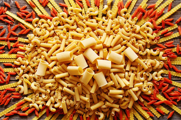 A lot of yellow and red italian pasta on a wood background