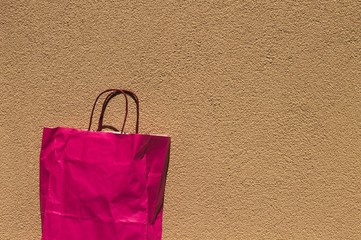 Isolated pink paper bag and brown wall background (Pesaro, Italy)