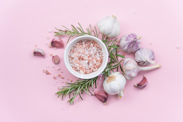 a composition of spices and herbs on a pink background, Himalayan salt with rosemary and garlic