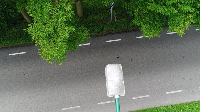 Aerial static footage above streetlight above rural road classic motorcycles and mopeds driving underneath the camera drone beautiful rural area during beautiful summer day 4k high resolution footage 