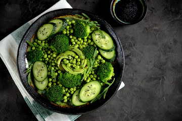 Healthy salad of broccoli, green peas, cucumber and avocado with arugula and olive oil. Healthy food. Top view
