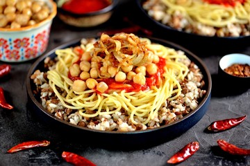 Kushari or Koushari - Egyptian dish of lentils, rice, pasta, chickpeas with tomato sauce and crispy onions. Arabic cuisine