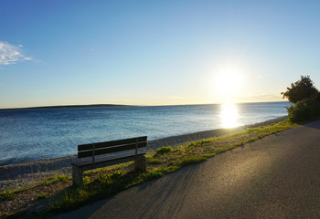 Bench in the seafront at sunset on the early summer windy day