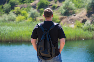 guy tourist on a cliff face looking at a pond, tourism, vacation, travel, summer vacation