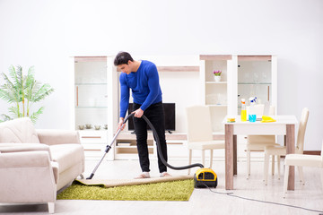 Young man vacuum cleaning his apartment