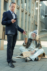 Rich and poor. Elderly rich successful businessman feeling helpful while giving some money to poor...