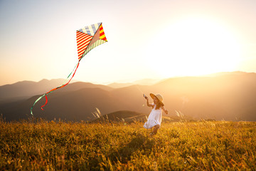 happy child girl running with kite at sunset outdoors