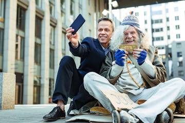 Encouraging man. Famous influencing charity man encouraging other people helping homeless while taking picture with street person