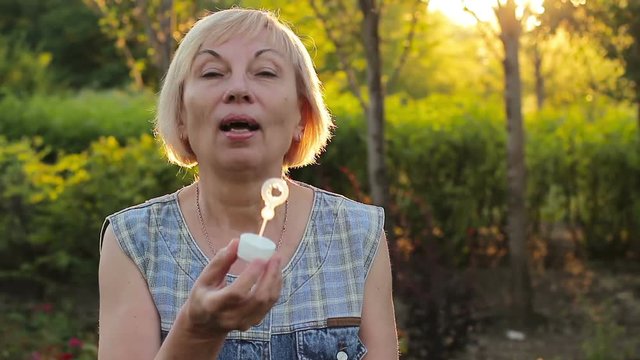 Emotional elderly woman blowing bubbles
