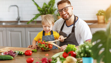 happy family father with son preparing vegetable salad