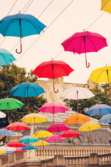 Fototapeta na wymiar Multi-colored umbrellas background. Colorful umbrellas floating above the street. Street decoration.