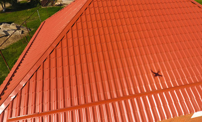Obraz na płótnie Canvas House with an orange roof made of metal, top view. Metallic profile painted corrugated on the roof