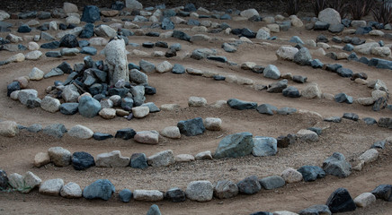 Traditional natural stone walking labyrinth maze made for contemplation and worship, created with rocks in shades of blue and turquoise.