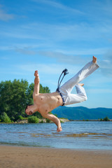 Man practicing capoeira on the beach. The man does the fighting element of capoeira.
