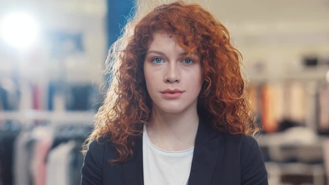 Portrait of red curly hair young woman look at camera at clothes store design girl shopping face spring customer light happy indoors female retail beautiful lifestyle pretty young adult cute lady