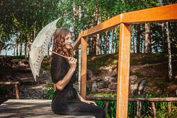young woman hiding from the sun under white lace umbrella