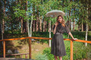 young woman hiding from the sun under white lace umbrella