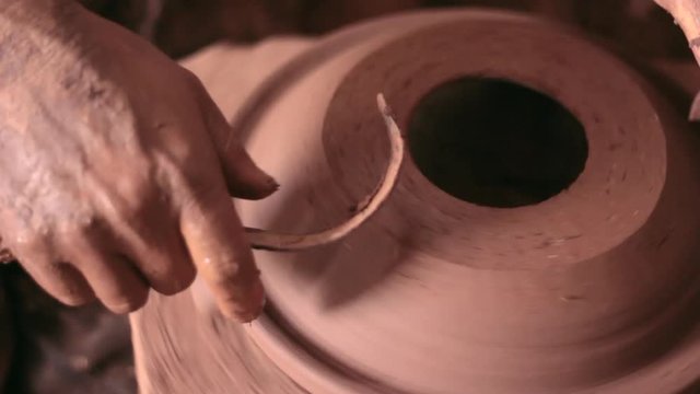 Potier qui gratte le surplus d'argile pour la finition de l'objet