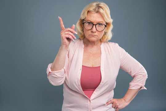 Mad At You. Angry Senior Woman Raising Her Index Finger And Being About To Scold Someone While Glaring