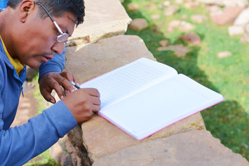 Illiterate native american man learning to write in the countryside. 