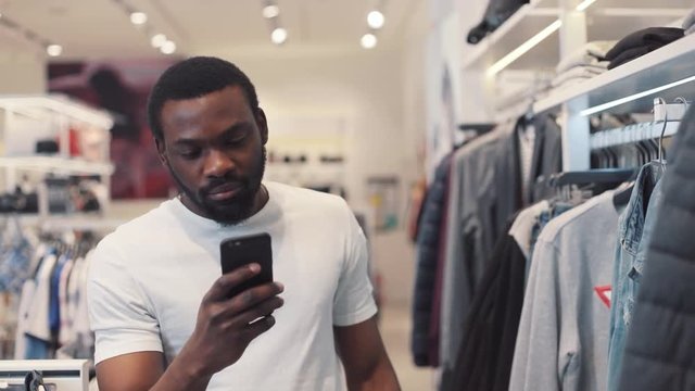 Close up african american young man using phone texting message walk at store chooses clothes internet happy black telephone portrait cute mobile holding slow motion portrait